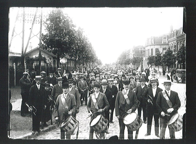 Foule et musiciens attendant les participants d'un concours de pêche à la sortie de la gare