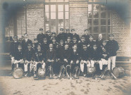 Groupe de musiciens d'une fanfare posant dans la cour d'un bâtiment endommagé