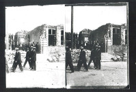 Groupe de personnalités passant devant un bâtiment en ruines