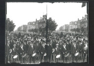 Foule et musiciens attendant les participants d'un concours de pêche à la sortie de la gare