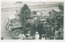 Groupe de personnes et de soldats sur un véhicule blindé célébrant la Libération de la ville