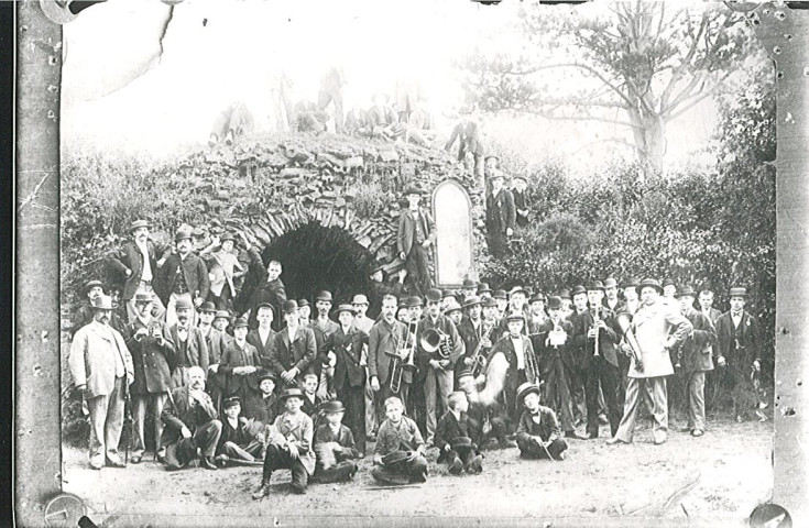 Groupe de musiciens posant devant la grotte de l'église Notre-Dame-de-Lourdes à La Choque