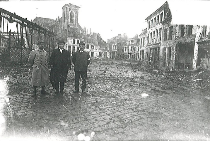 Personnes devant les halles et l'église Saint-Vaast en ruines