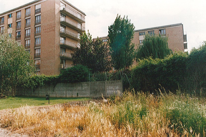 Terrain en friche après le comblement de la Lys au centre-ville et vue sur les résidences de la Lys